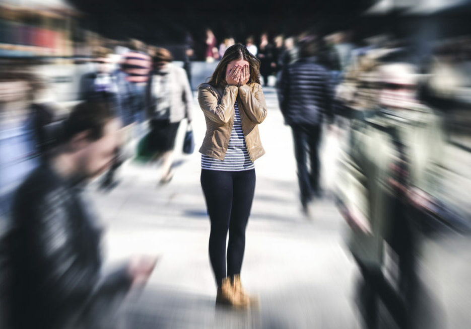 Panic attack in public place. Woman having panic disorder in city. Psychology, solitude, fear or mental health problems concept. Depressed sad person surrounded by people walking in busy street.